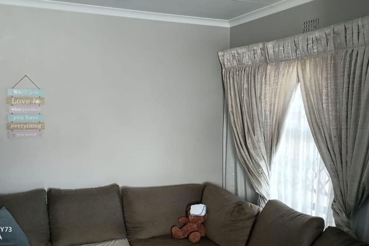 A living room area featuring neutral wall paint, cove cornicing, and window treatments.