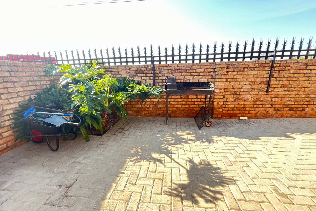 A private rear courtyard featuring a brick boundary wall with security spikes and durable paved flooring, offering a functional outdoor space.
