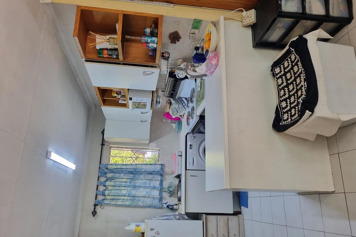 A compact kitchen featuring white cabinetry, a built-in stove, and tiled flooring, offering a functional layout with potential for modernization.