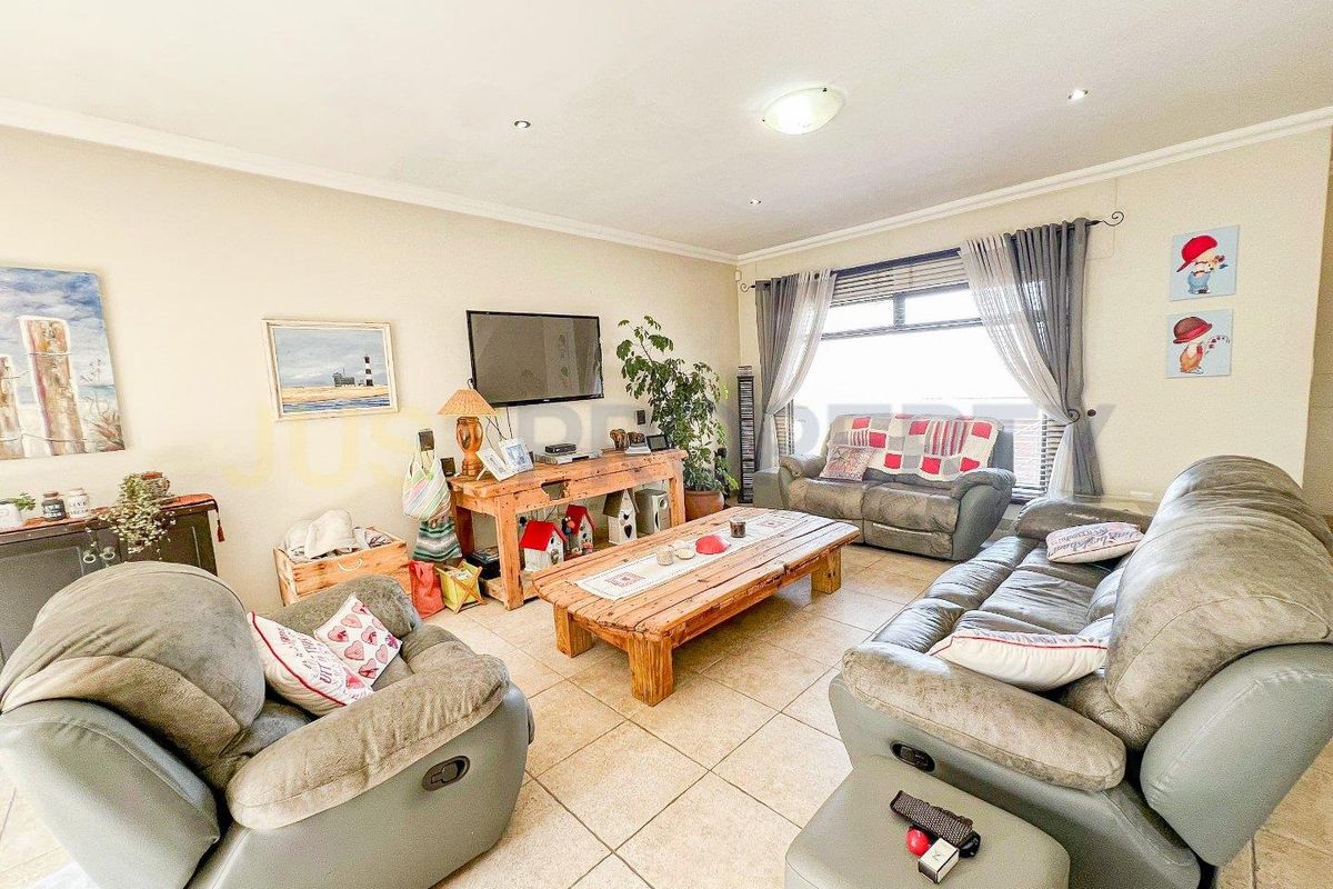 A spacious living room featuring tiled flooring, large windows with curtains, and recessed ceiling lighting, providing a comfortable and functional living area.