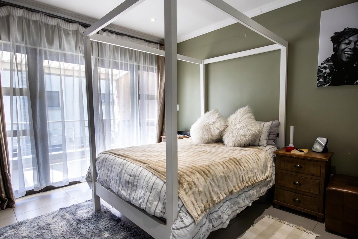 A well-lit bedroom featuring tiled flooring and a large sliding glass door providing access to an outdoor area.