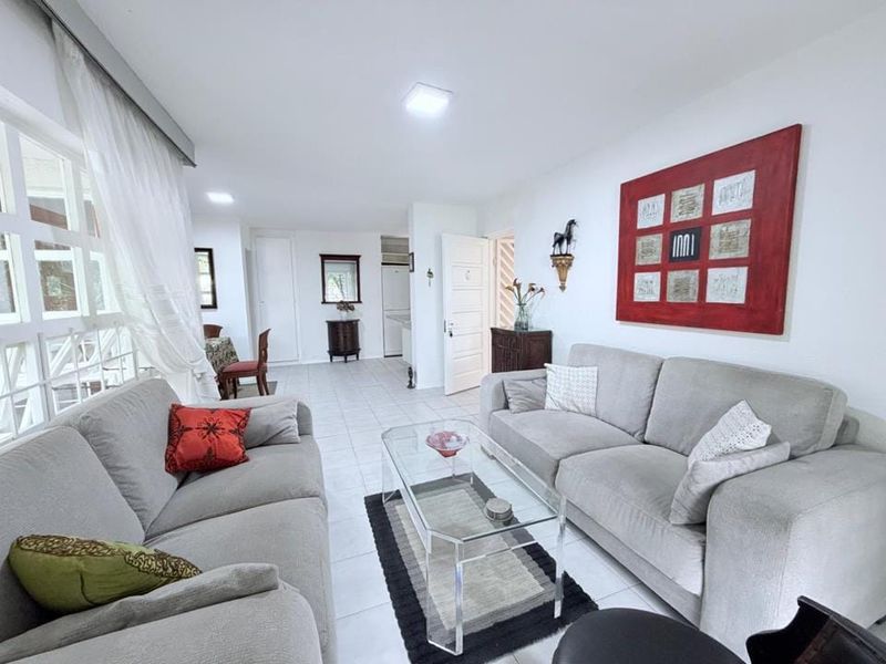 A bright and spacious living room featuring tiled flooring, recessed lighting, and large windows that allow for ample natural light.