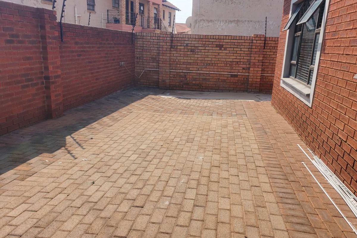 A paved rear courtyard area enclosed by high brick boundary walls with integrated electric fencing.