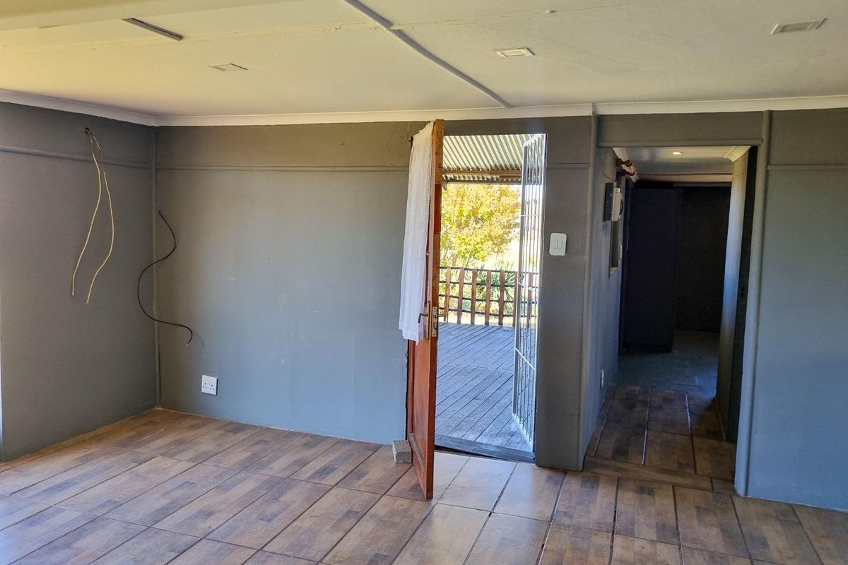An interior living space featuring wood-look tiled flooring, grey painted walls, and direct access to an outdoor deck area.