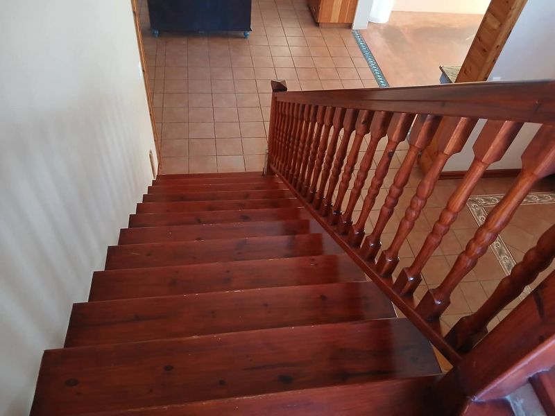 A view looking down a wooden staircase with a matching balustrade, leading to a tiled lower level hallway.