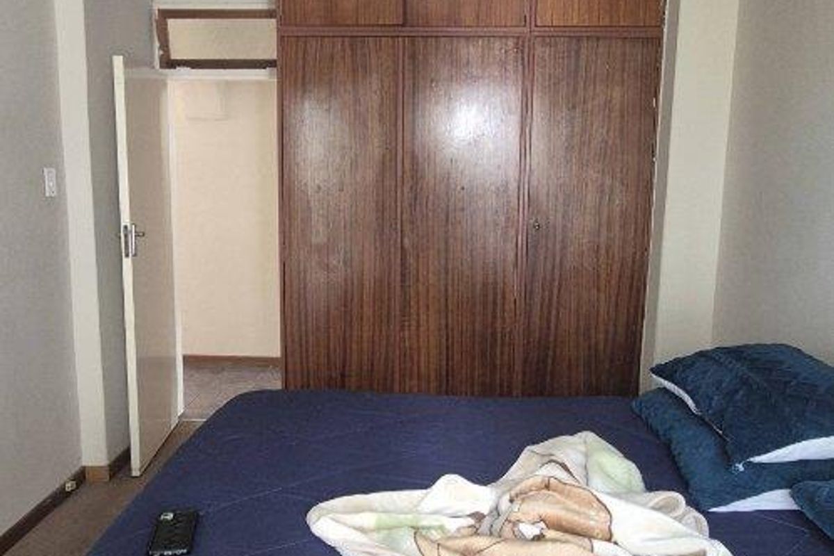 A bedroom featuring built-in wooden cabinetry with overhead storage, providing functional storage space within the room.