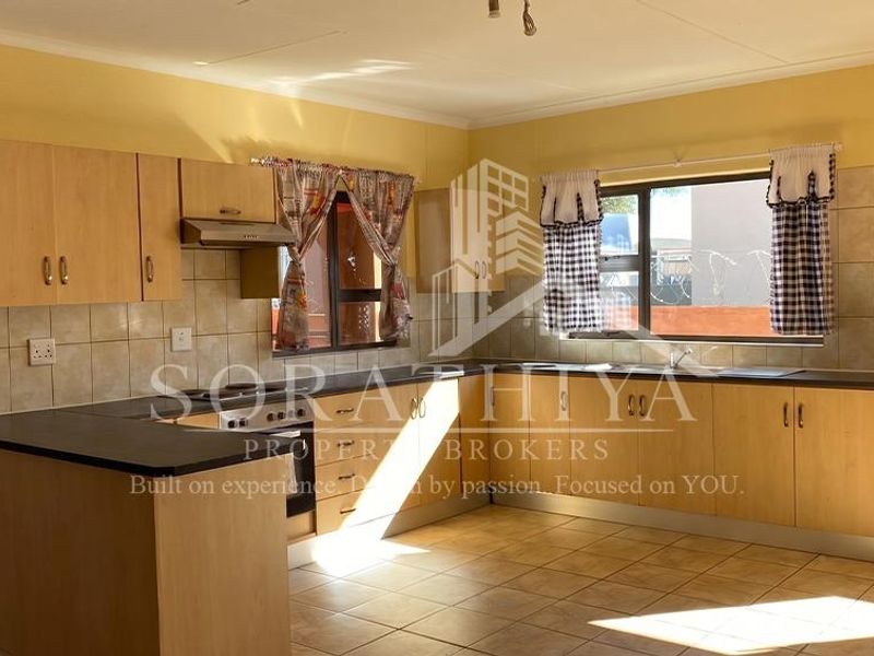 A functional kitchen featuring laminate cabinetry, a built-in oven, extractor fan, and tiled backsplash, offering a clean and practical layout.