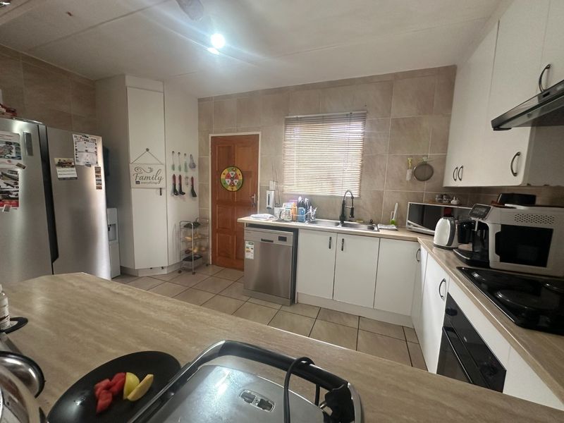Functional kitchen featuring white cabinetry, laminate countertops, tiled backsplash, and integrated appliances, offering a practical layout for daily cooking and preparation.