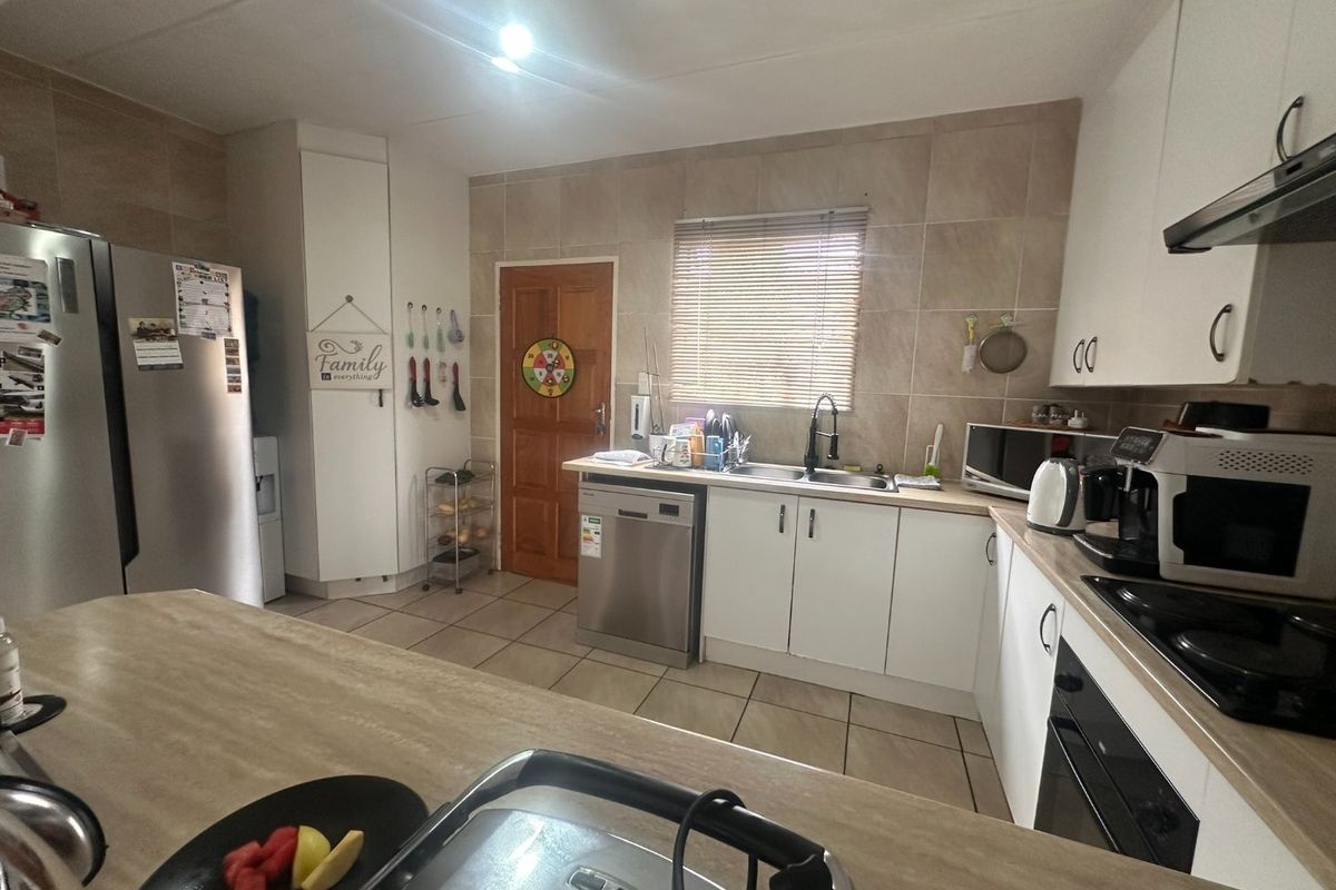 Functional kitchen featuring white cabinetry, laminate countertops, tiled backsplash, and integrated appliances, offering a practical layout for daily cooking and preparation.