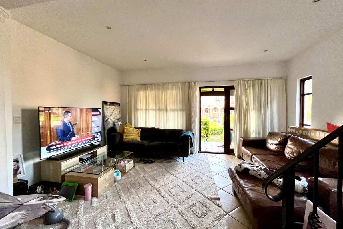 A spacious living room featuring tiled flooring, recessed lighting, and direct access to an outdoor patio area through a glass-paneled door.