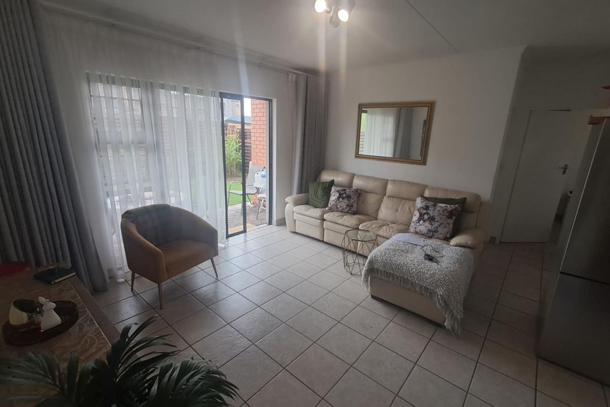 A bright living room featuring tiled flooring and large sliding glass doors that provide direct access to the outdoor patio area.
