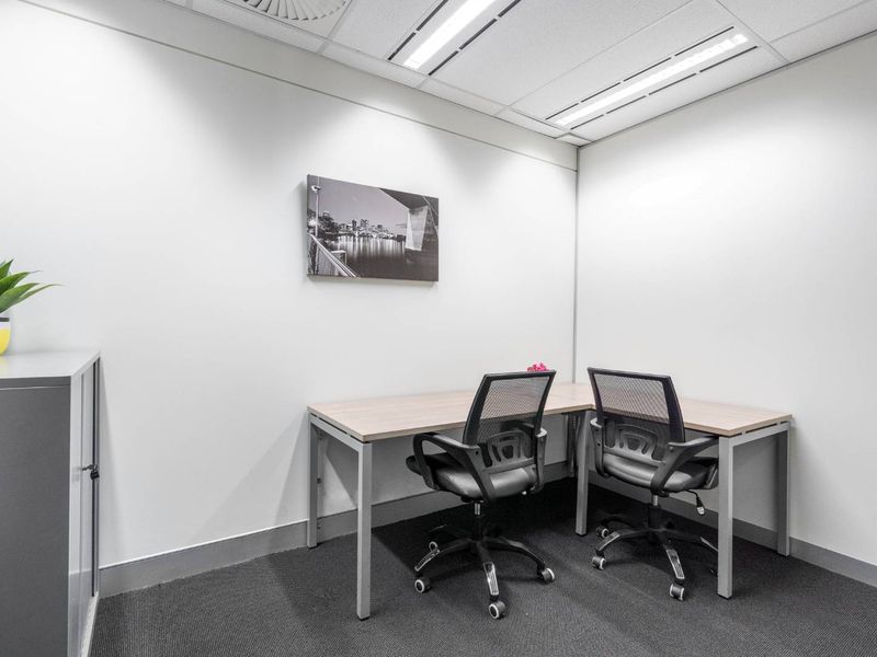 A clean, professional office space featuring neutral walls, carpeted flooring, and recessed ceiling lighting, suitable for a productive work environment.