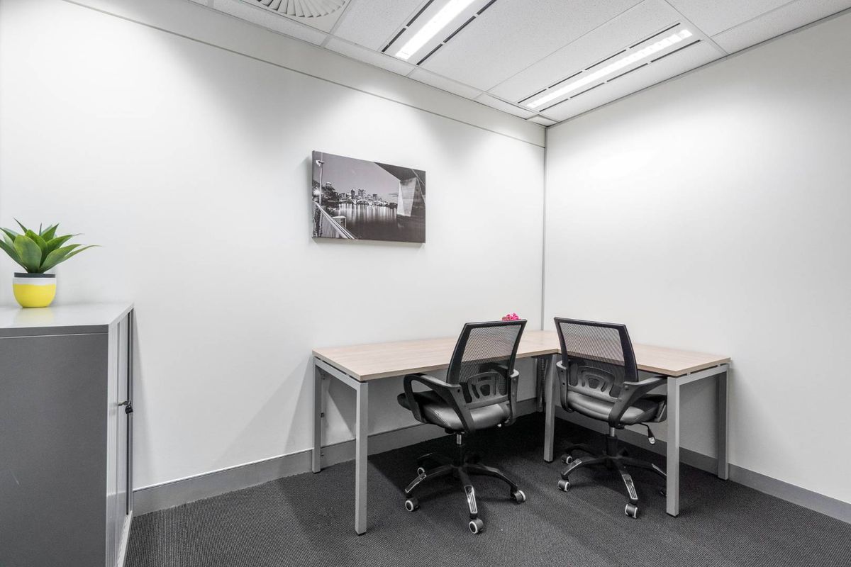 A clean, professional office space featuring neutral walls, carpeted flooring, and recessed ceiling lighting, suitable for a productive work environment.