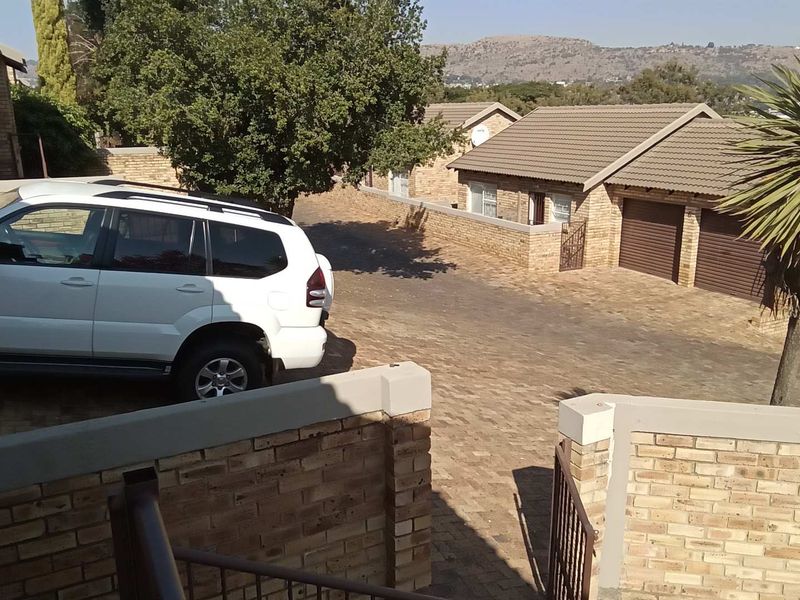 View of the townhouse complex driveway featuring brick paving, boundary walls, and garage access.