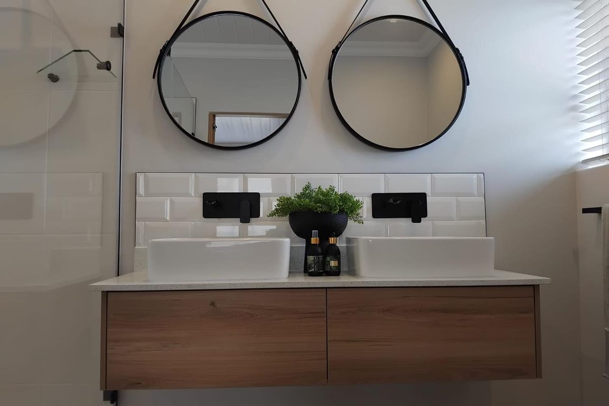 Modern bathroom featuring a floating timber vanity with dual vessel sinks, matte black wall-mounted faucets, and subway tile backsplash.