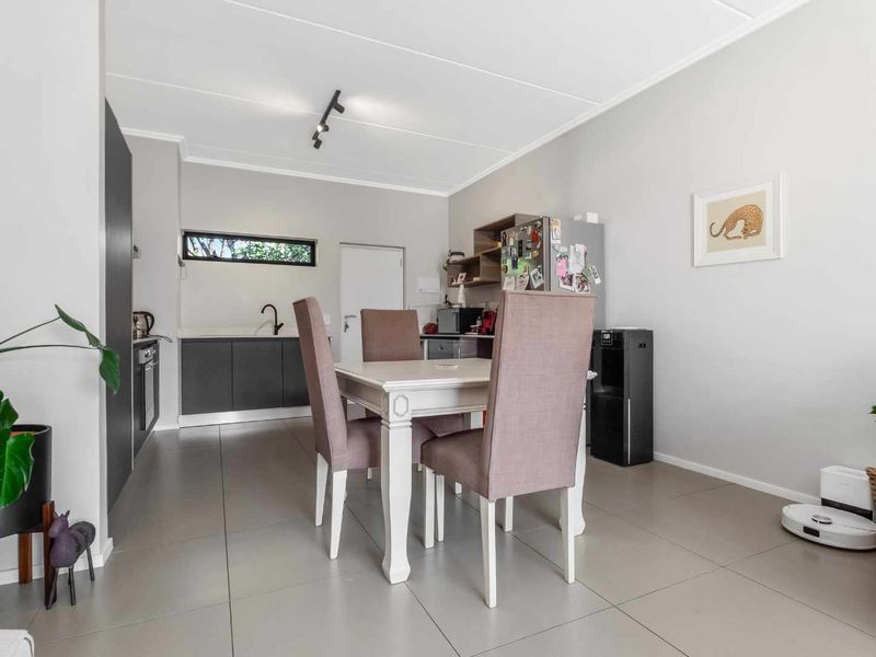 An open-plan living and kitchen area featuring modern grey cabinetry, tiled flooring, and a functional layout with integrated kitchen appliances.