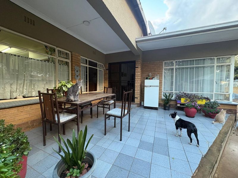 A covered outdoor patio area featuring tiled flooring and brick exterior walls, providing a functional space for outdoor living and entertainment.