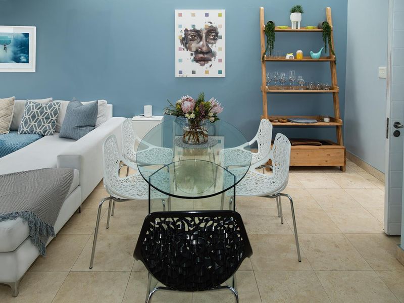 A well-maintained open-plan living and dining area featuring neutral tiled flooring and a contemporary blue feature wall.