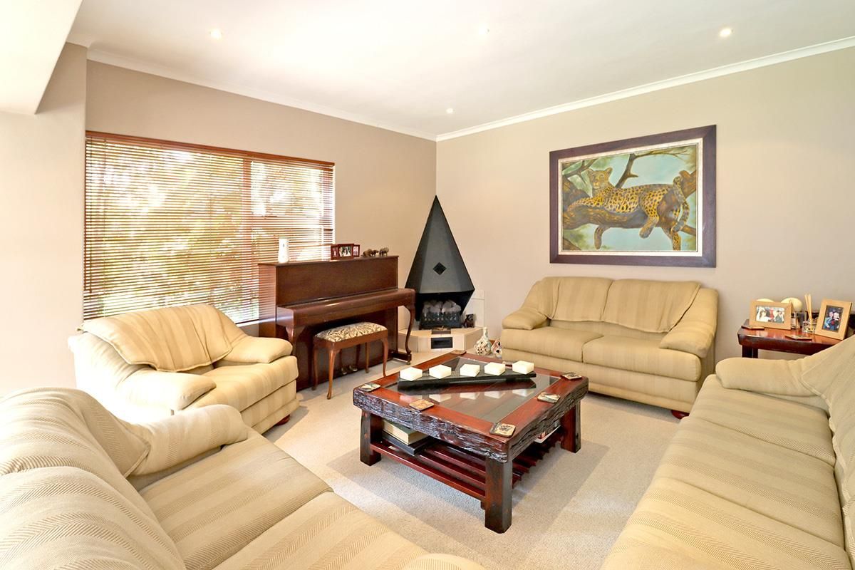 A comfortable living room featuring a corner fireplace, neutral wall tones, and large windows with fitted blinds.