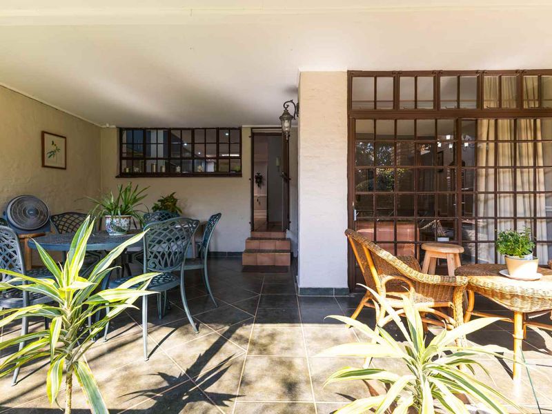 A covered patio area featuring tiled flooring and timber-framed glass doors providing access to the interior living space.