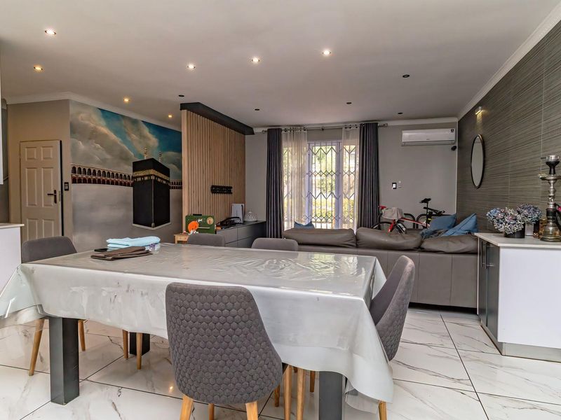 Spacious open-plan living and dining area featuring modern tiled flooring, recessed lighting, an air conditioning unit, and a decorative timber feature wall.