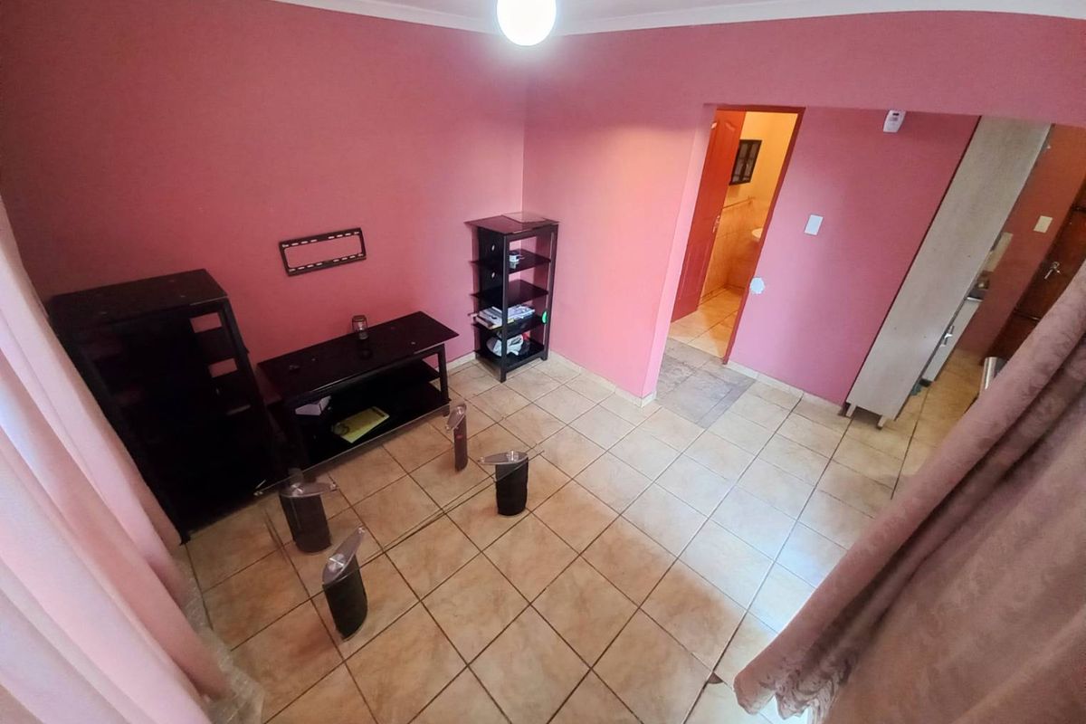 A living room featuring ceramic floor tiles and pink wall finishes, with direct access to an adjacent room.