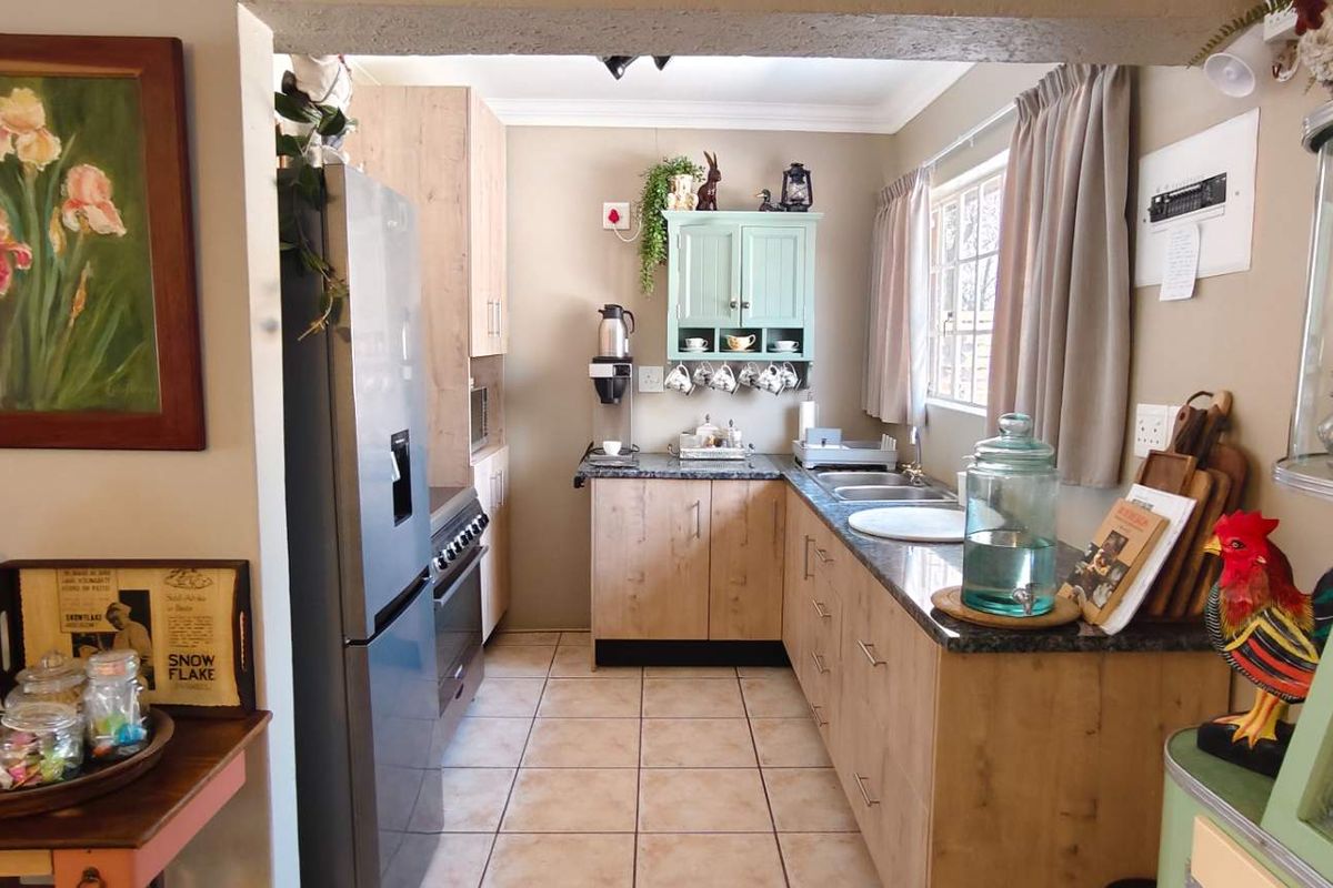 A functional kitchen featuring light wood-look cabinetry, granite countertops, a double sink, and built-in oven, finished with neutral tiled flooring.