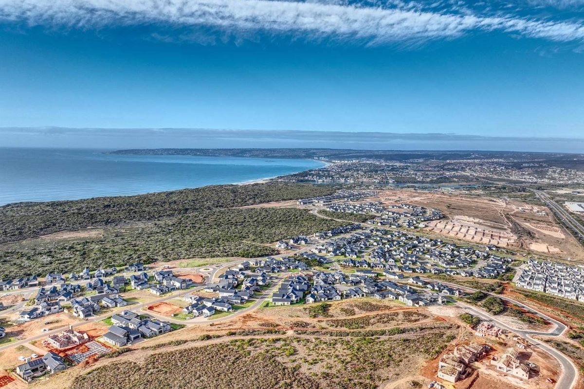 An expansive aerial view of a coastal residential development, showcasing the surrounding landscape, proximity to the ocean, and ongoing construction of new homes.