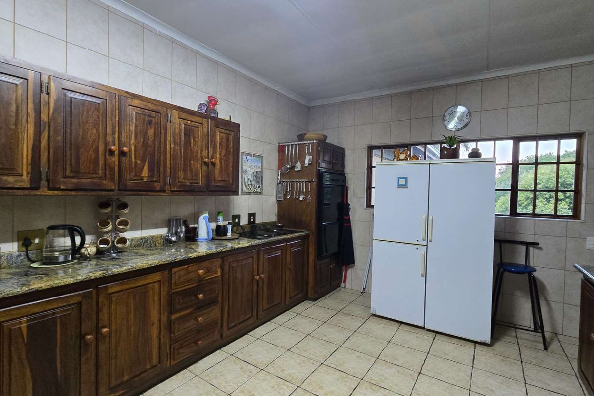A functional kitchen featuring traditional wooden cabinetry, granite countertops, tiled walls, and built-in oven, offering a classic aesthetic with potential for modern updates.