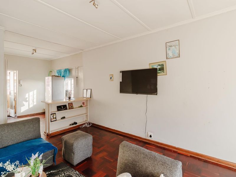Open plan living area featuring dark parquet flooring and a built-in breakfast bar, connecting to a kitchen space.