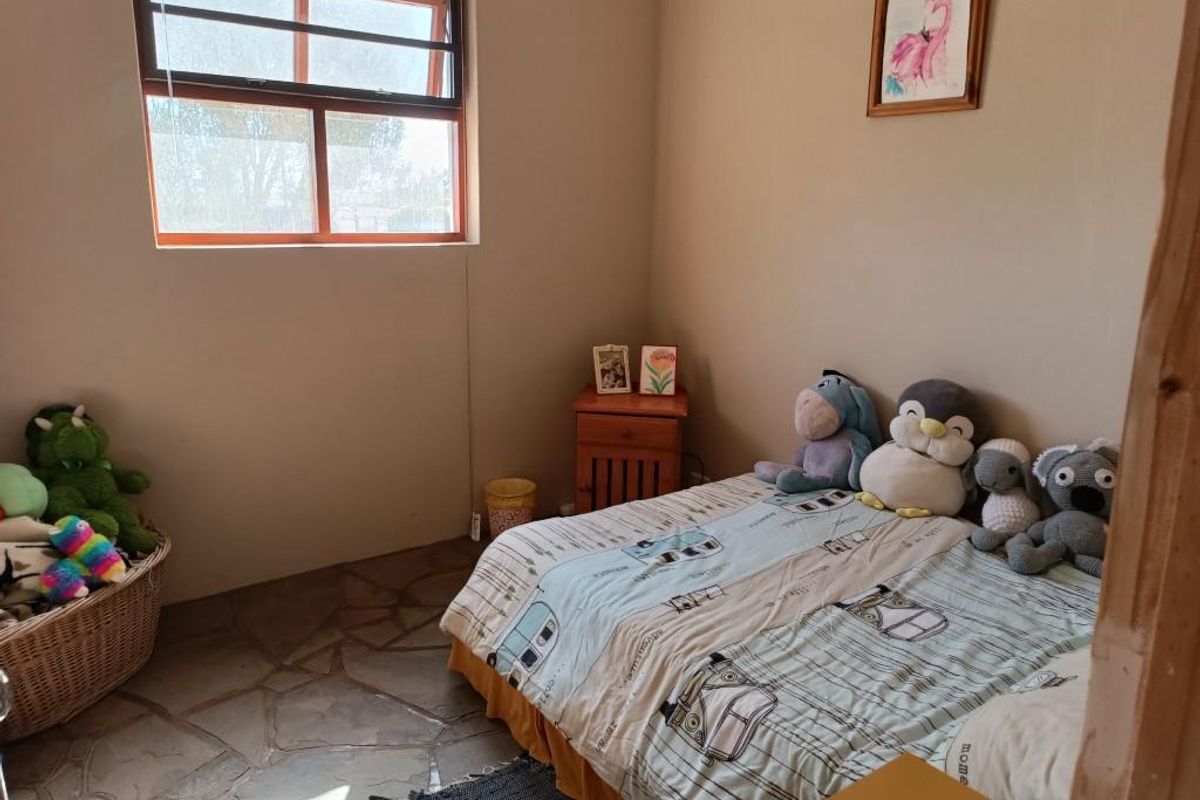 A bedroom featuring natural stone flooring and a large window, providing a rustic and cozy atmosphere.