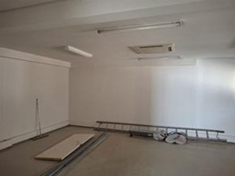 An empty office space featuring recessed ceiling air conditioning and strip lighting, providing a clean, functional environment for professional use.