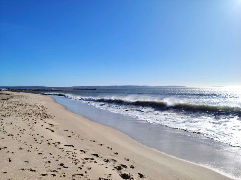 A scenic view of the sandy coastline and ocean waves, highlighting the natural landscape and beach access associated with the property.