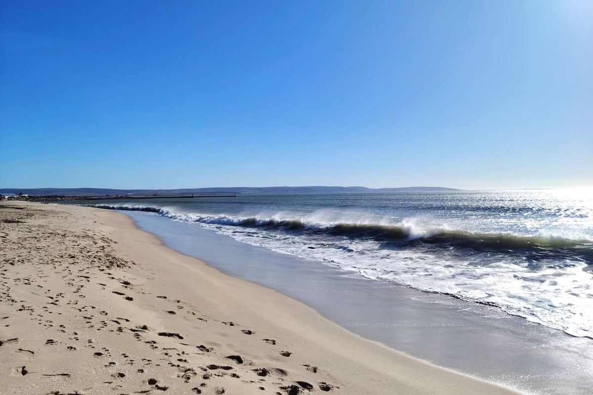 A scenic view of the sandy coastline and ocean waves, highlighting the natural landscape and beach access associated with the property.