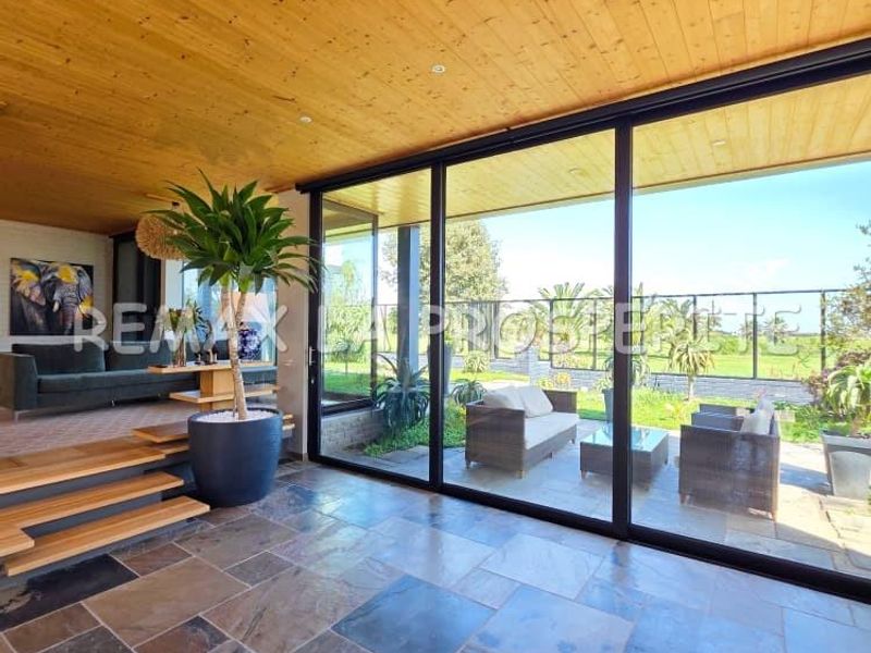 Spacious living area featuring natural slate flooring, a warm timber-clad ceiling, and expansive sliding glass doors that provide seamless access to the outdoor patio.