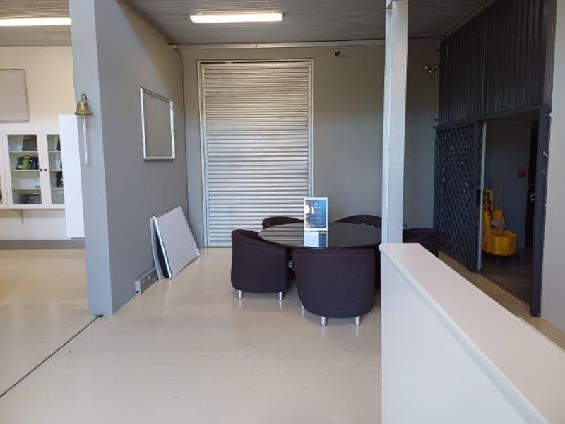 An office space featuring a roller shutter door, security gate, and built-in cabinetry, providing a functional and secure work environment.