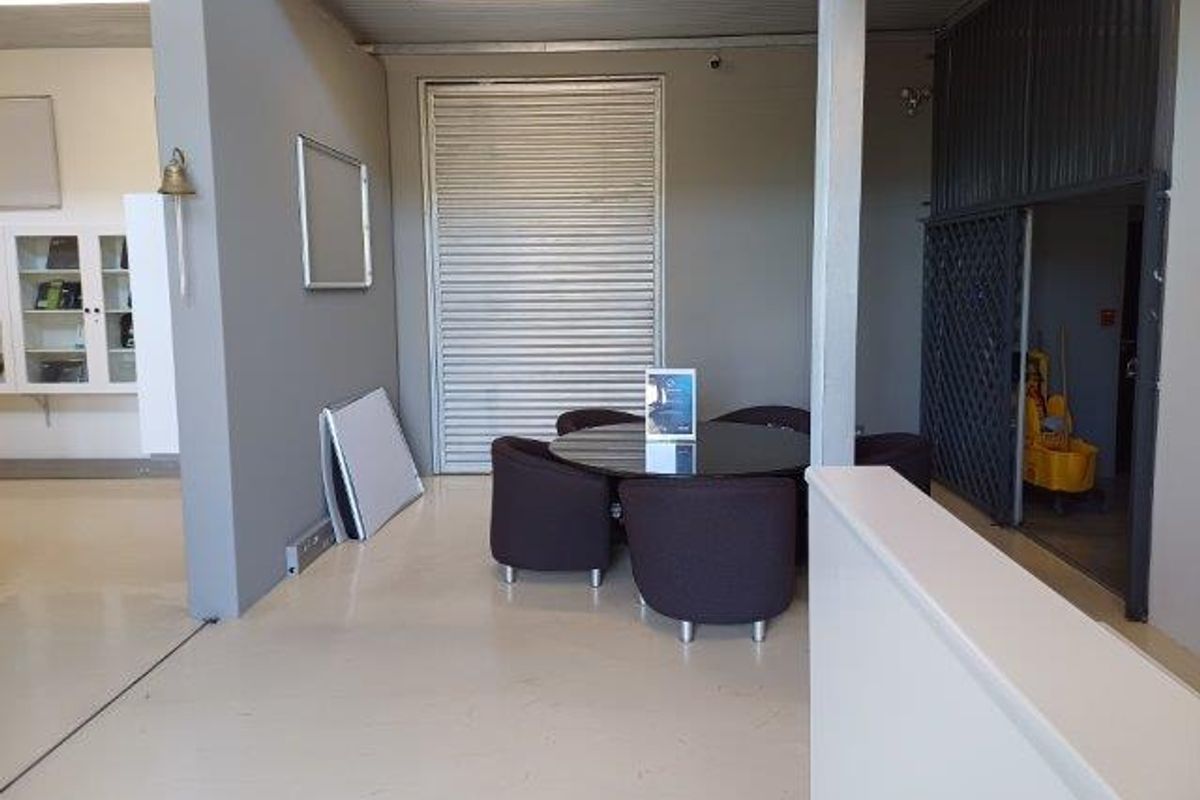 An office space featuring a roller shutter door, security gate, and built-in cabinetry, providing a functional and secure work environment.