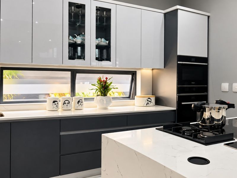 Modern kitchen featuring high-gloss cabinetry, quartz countertops, integrated appliances, and a sleek gas hob on a central island with under-cabinet lighting.
