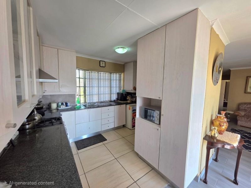 A functional kitchen featuring light-toned laminate cabinetry, granite countertops, a gas hob, and a built-in microwave with tiled flooring.