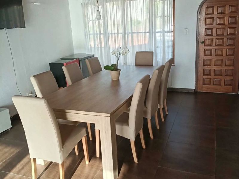 Spacious dining area featuring dark tiled flooring, a warm timber ceiling, and a classic arched wooden entrance door.