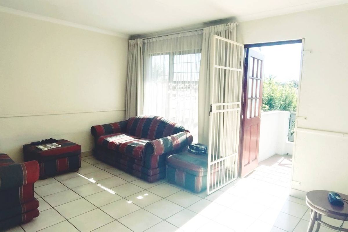 A living room featuring tiled flooring and direct access to an outdoor area through a security gate and sliding door.