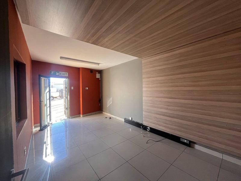 A bright, empty office space featuring modern wood-look wall and ceiling paneling, polished tiled flooring, and integrated electrical trunking.