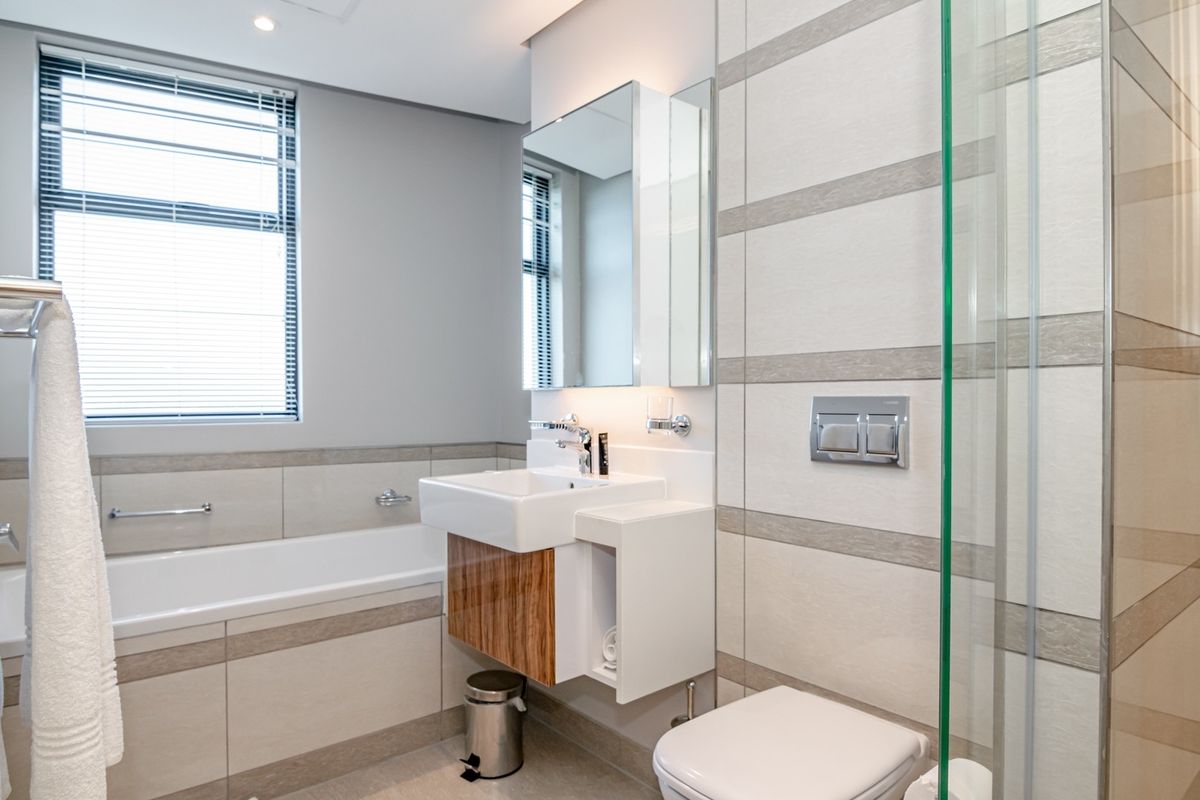 Modern bathroom featuring a wall-mounted vanity, integrated mirror cabinet, bathtub, and a glass-enclosed shower with contemporary wall tiling.