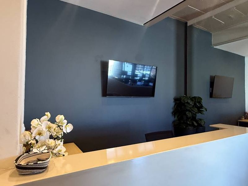 A modern reception area featuring a clean desk, recessed ceiling lighting, and wall-mounted screens, creating a professional and welcoming entrance space.