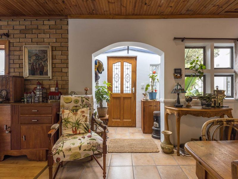 Welcoming entrance hall featuring a timber ceiling, exposed brick accent wall, tiled flooring, and an arched doorway leading to a timber front door.
