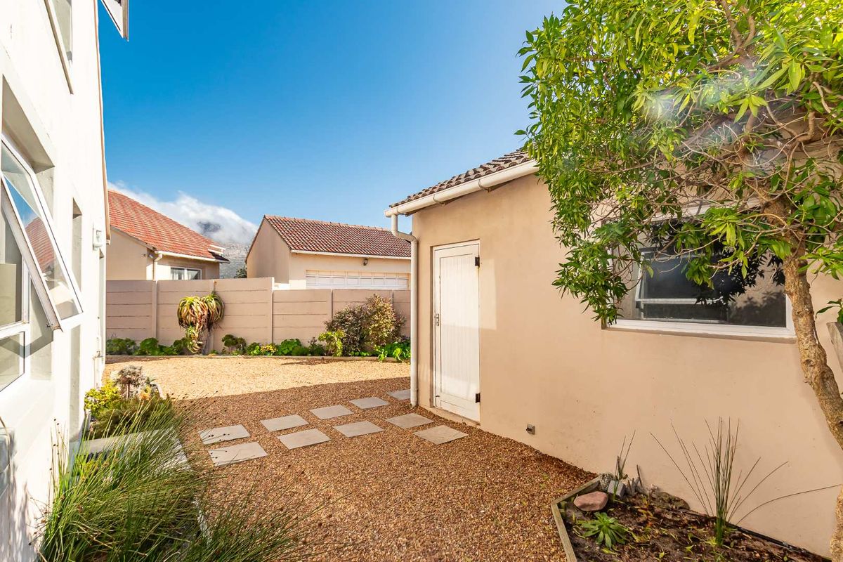 A low-maintenance rear courtyard featuring gravel landscaping, paved stepping stones, and a side access door to the property.