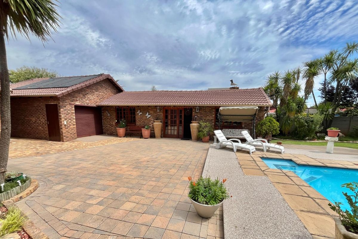 A well-maintained brick exterior featuring a paved courtyard, swimming pool, and integrated garage, offering a functional outdoor entertainment space.