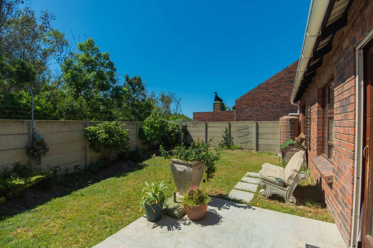 A private rear garden featuring a concrete patio area, lawn, and perimeter boundary walling, providing a functional outdoor space for the townhouse.