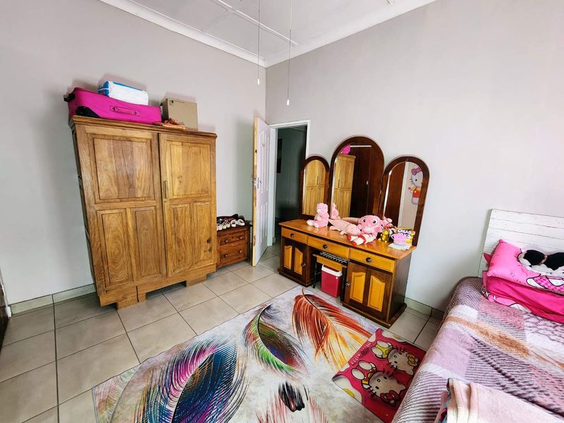 A bedroom featuring tiled flooring and coved ceiling details, providing a functional space with neutral wall finishes.