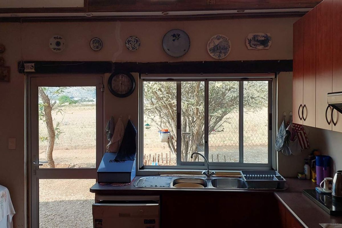 A functional kitchen featuring wood-tone cabinetry, a double-basin sink, and an integrated extractor fan, with direct access to the exterior.